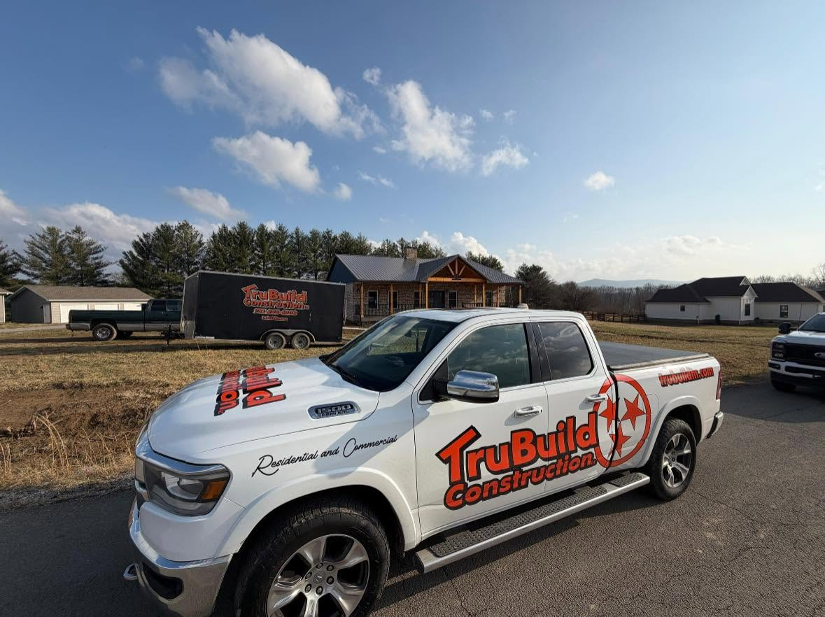 TruBuild Construction truck and trailer parked in front of a completed custom home in Middle Tennessee